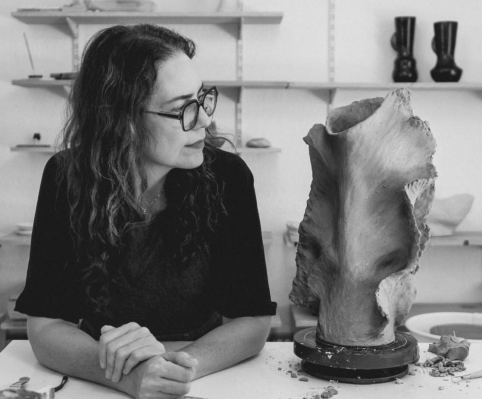 Ana Saldaña en su taller de cerámica, mirando una de sus esculturas de barro